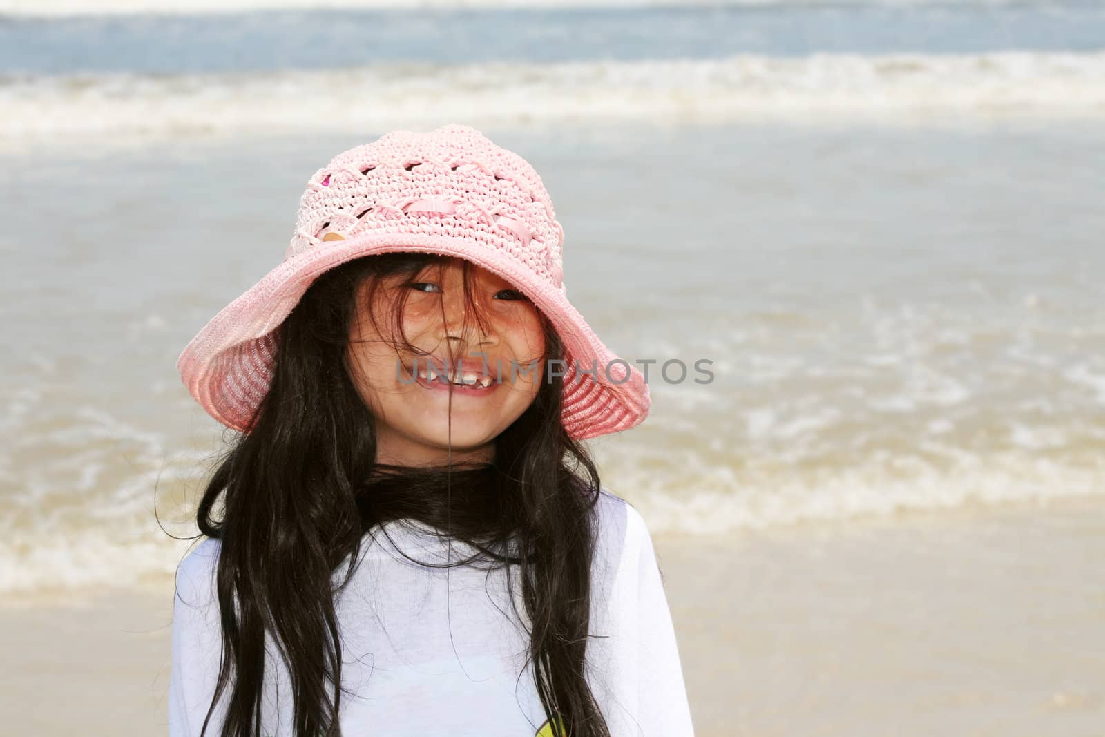 Cute little girl in pink hat at beach