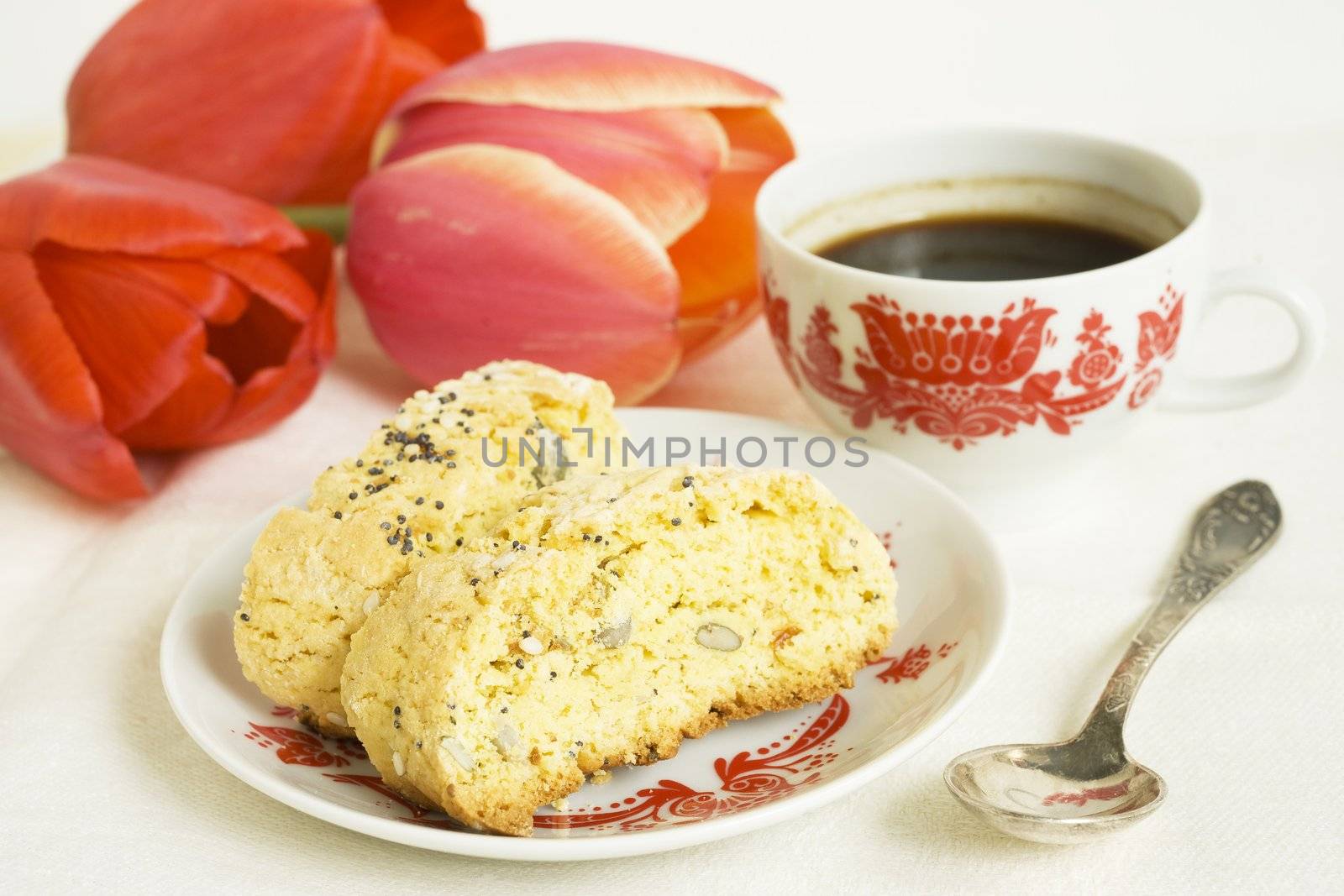 Corn biscotti with coffee cup and red tulips on the table
