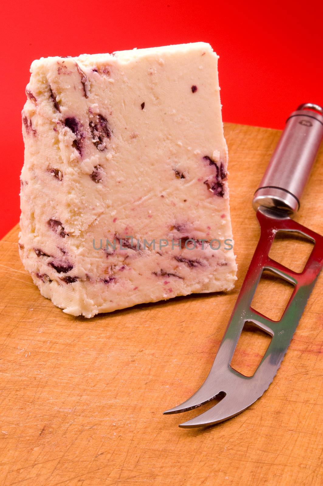 
	
Chader cheese with cranberries and a knife lying on a wooden board