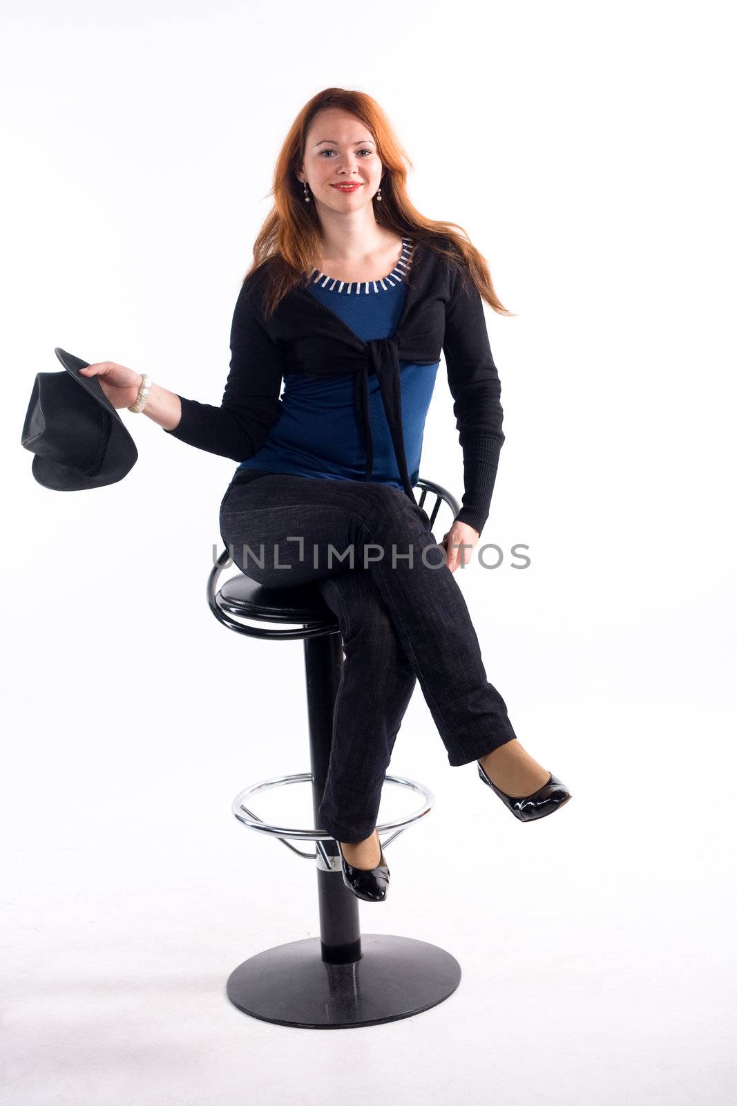 Young girl with  black hat sitting on chair on white background
