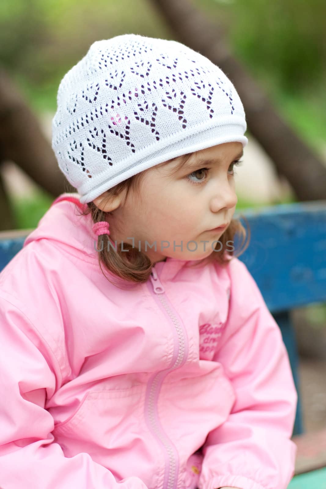 Thoughtful 3-year old little girl sitting and looking at far away during a walking outdoor