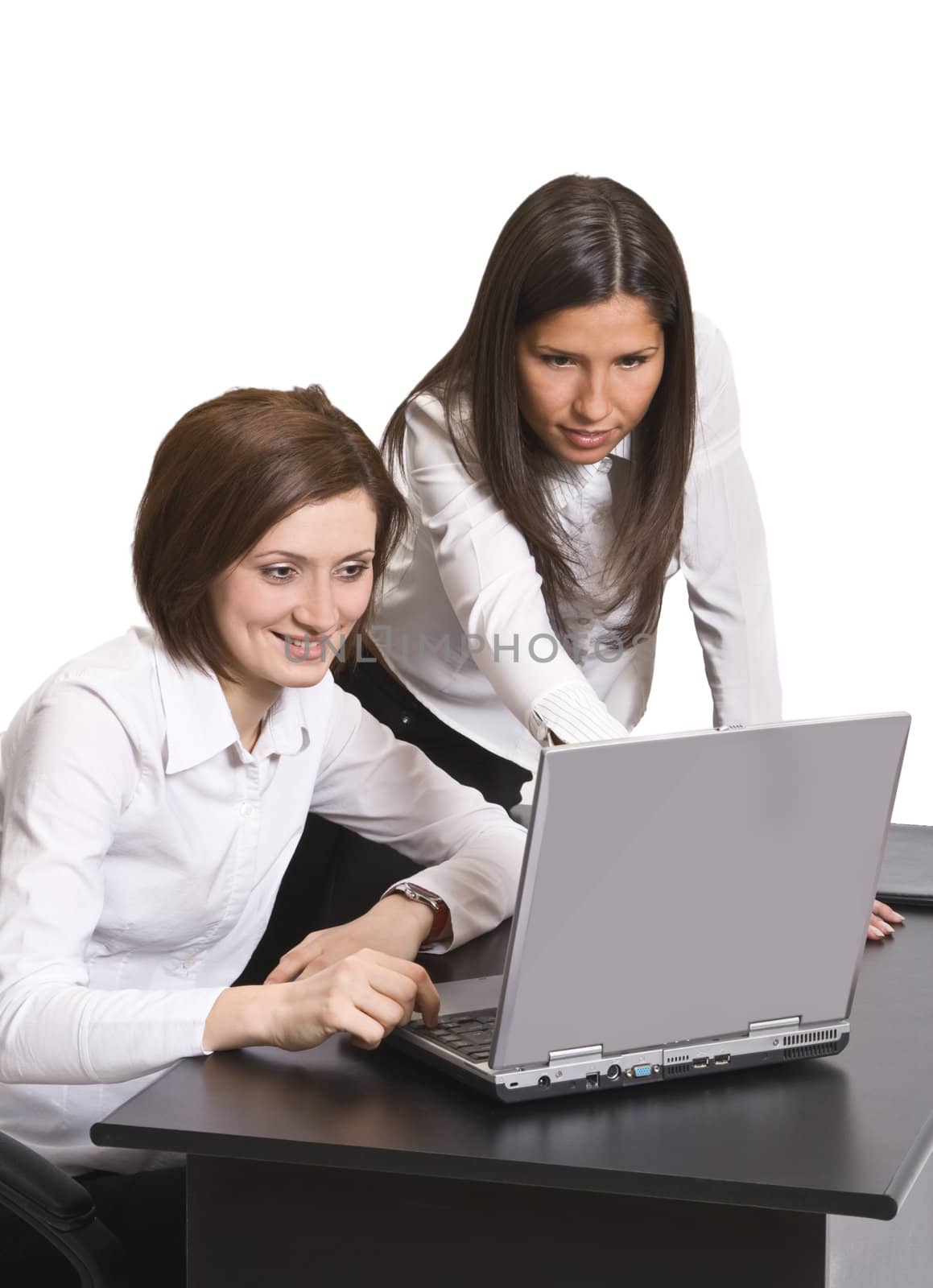 Two young businesswoman working together on a laptop at their office desk.