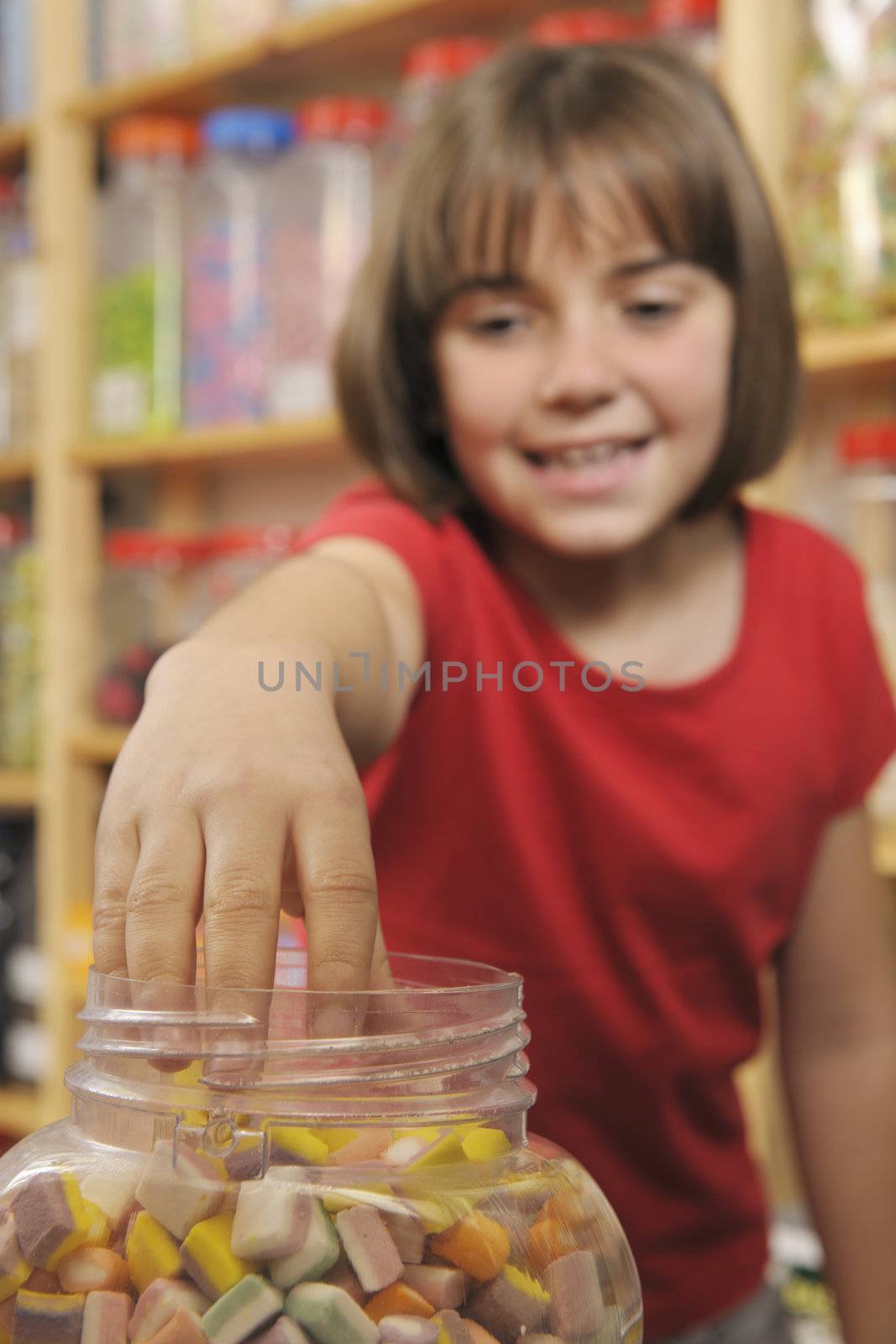 young girl grabbing sweets from a jar in a shop