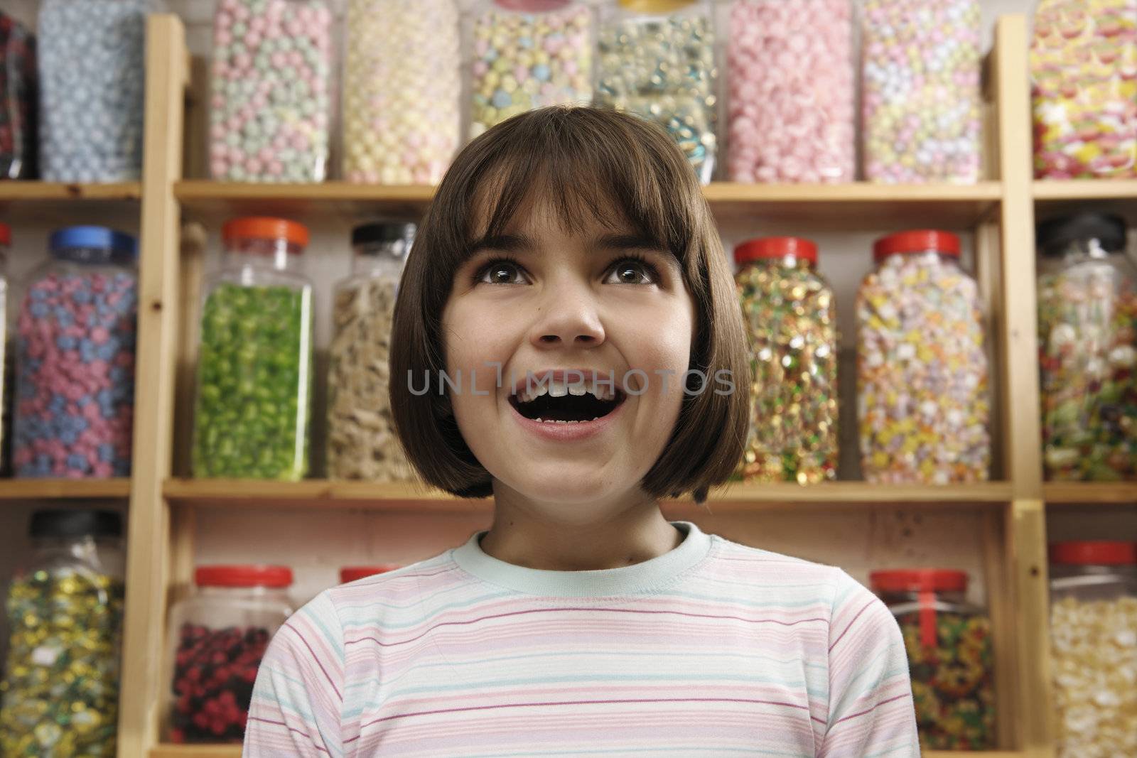 young girl smiling in awe at rows of sweets