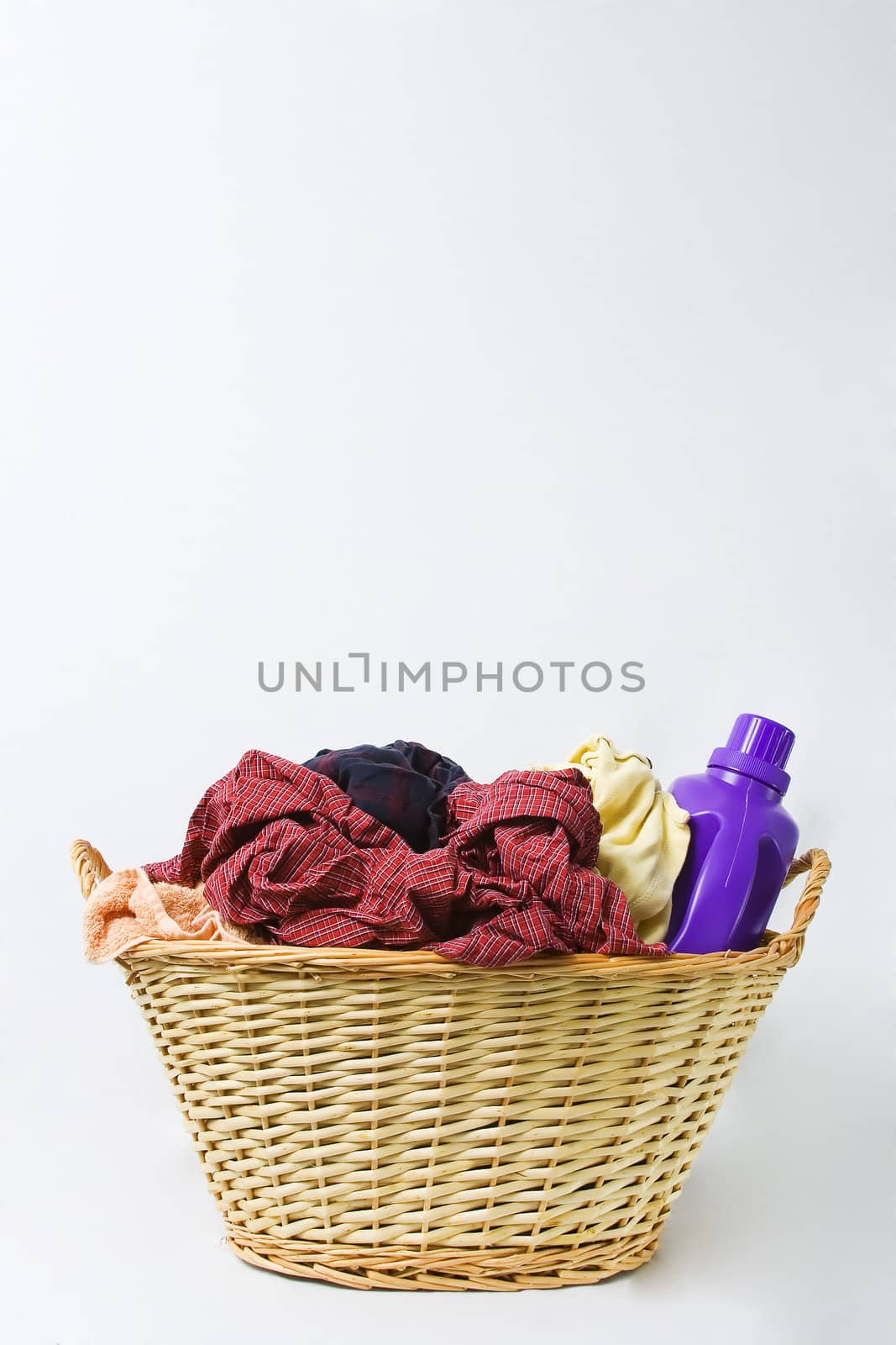 A vertical shot of a basket of dirty laundry and detergent.