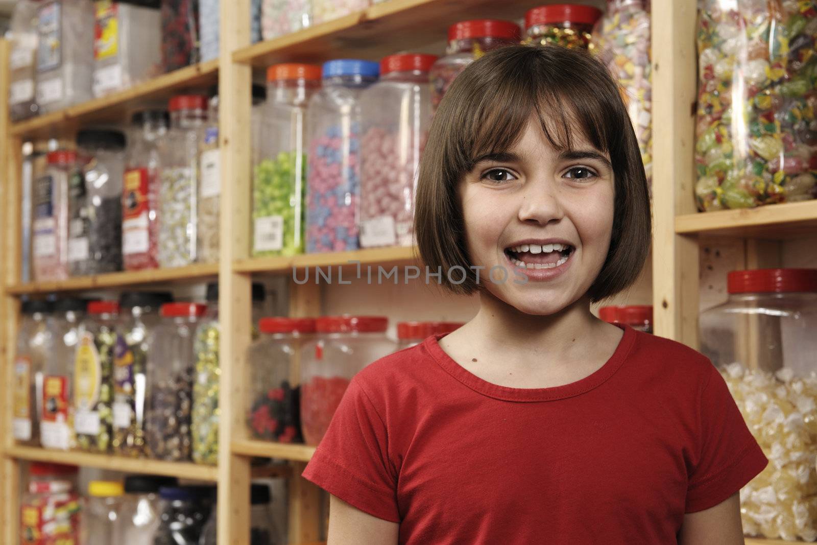 young girl smiling at camera in sweet shop  