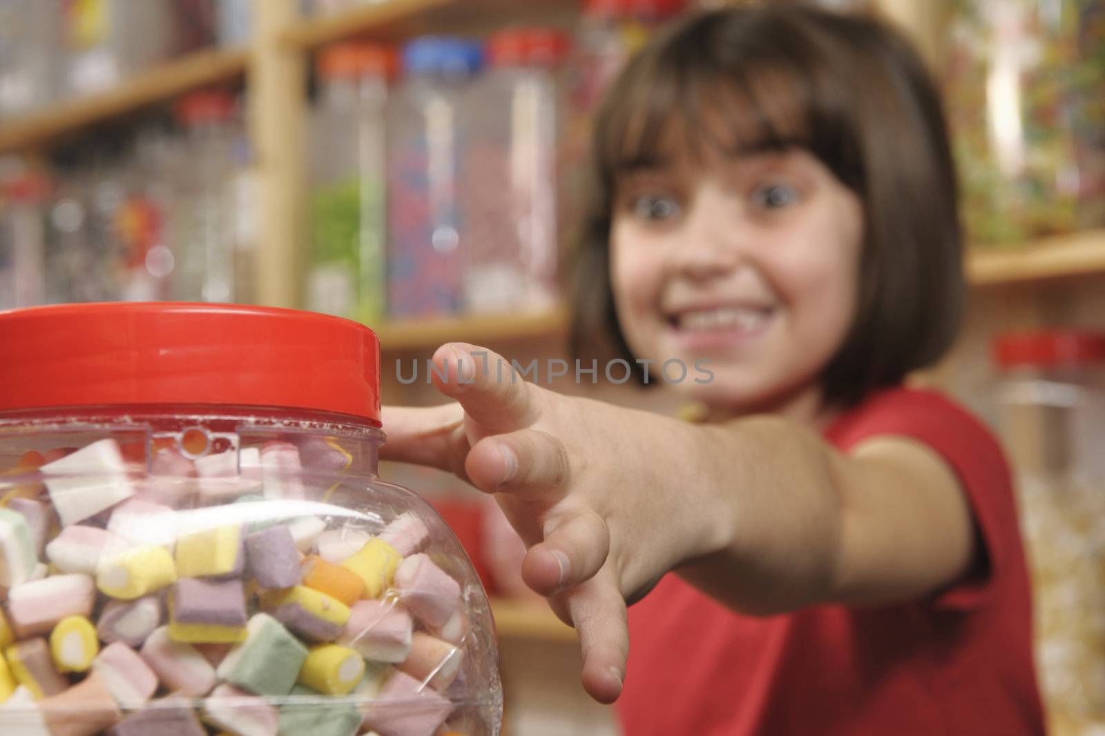 young girl grabbing a jar of sweets in shop
