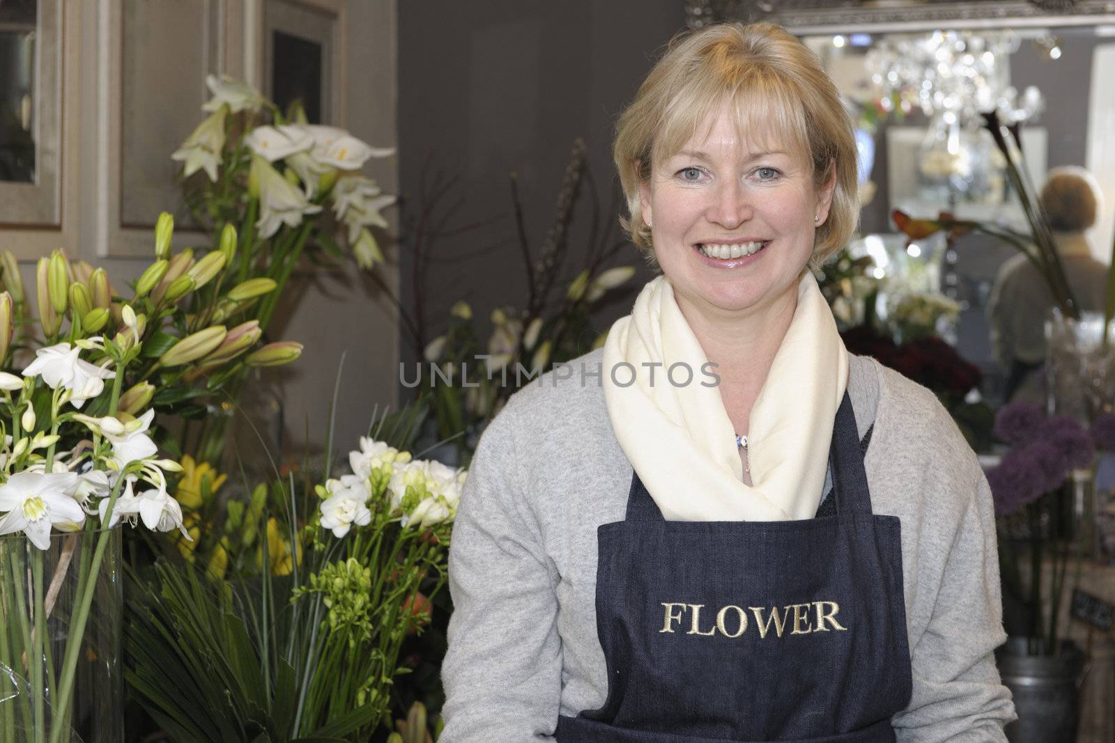 Florist in her shop surrounded by flowers smiling at camera