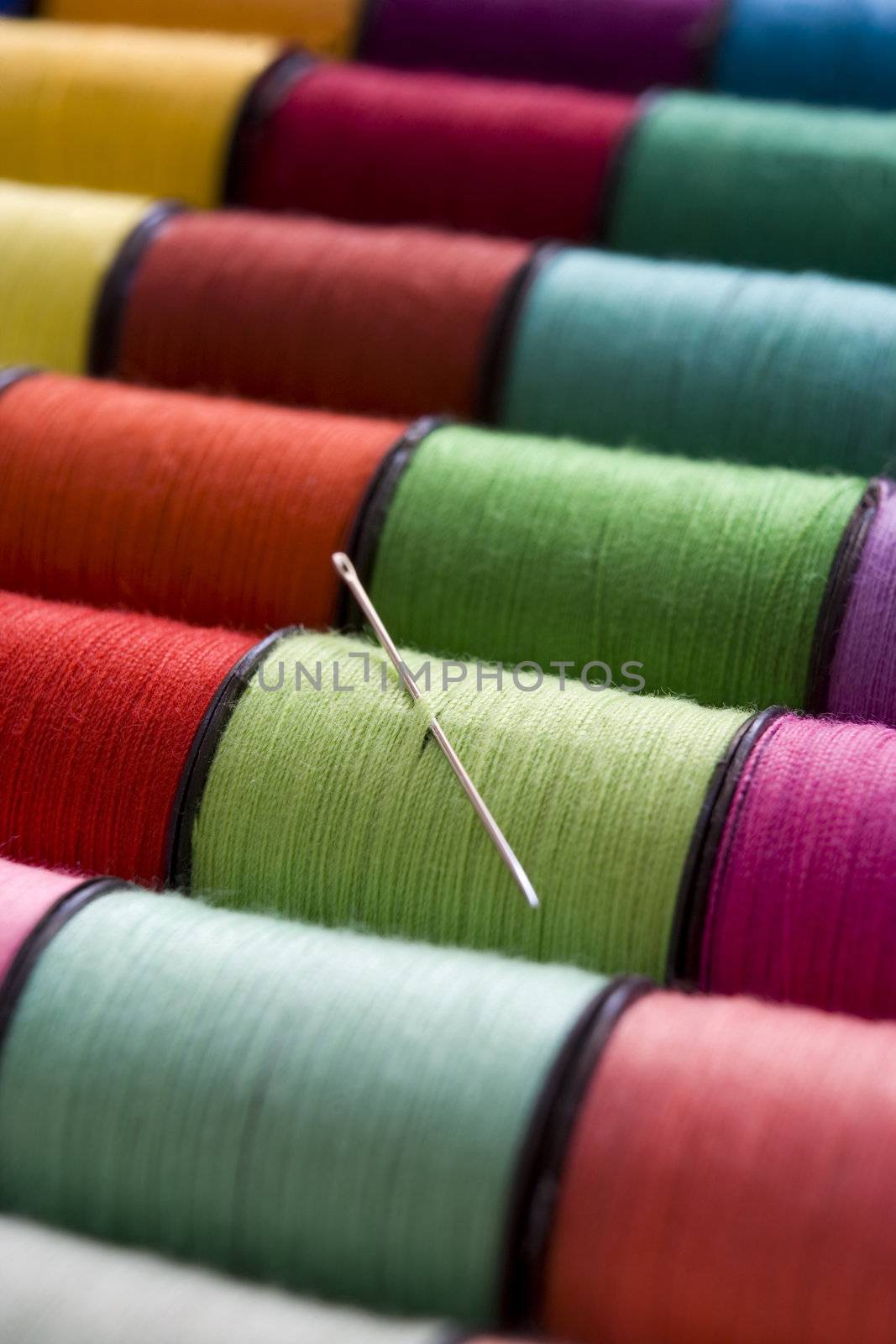 various colours of cotton reelsin a row with a needle