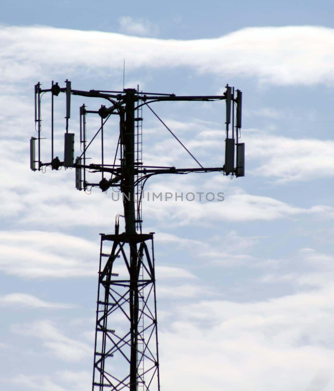 The top of a cell phone tower against a blue sky.