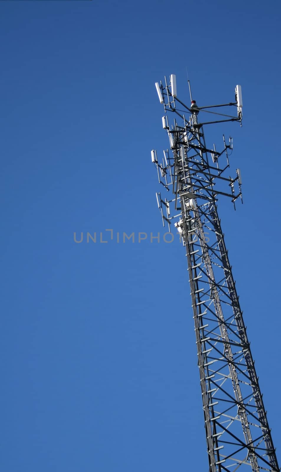 A cell phone tower set against a blue sky background.
