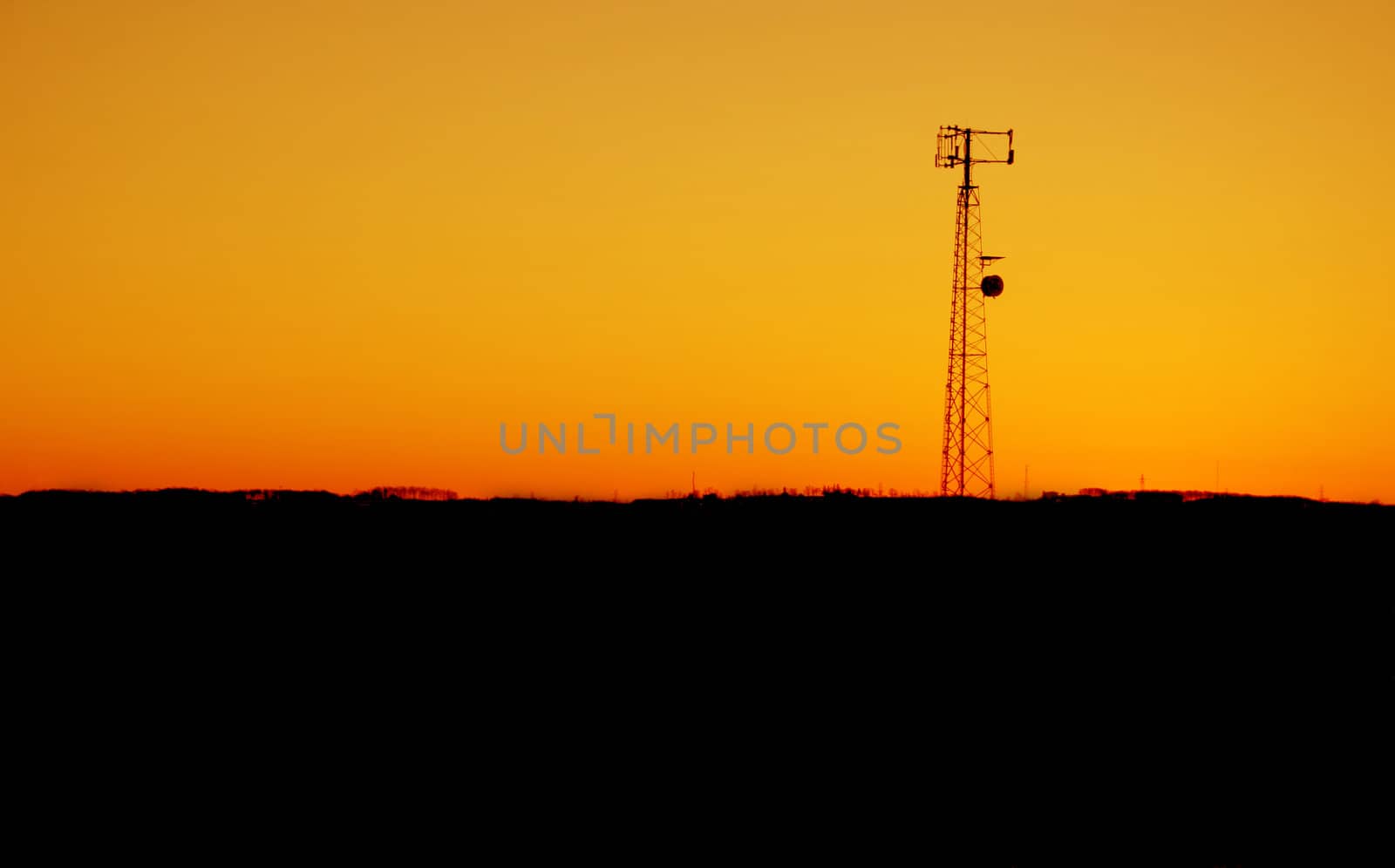 A cell phone tower silhouette in the sunset
