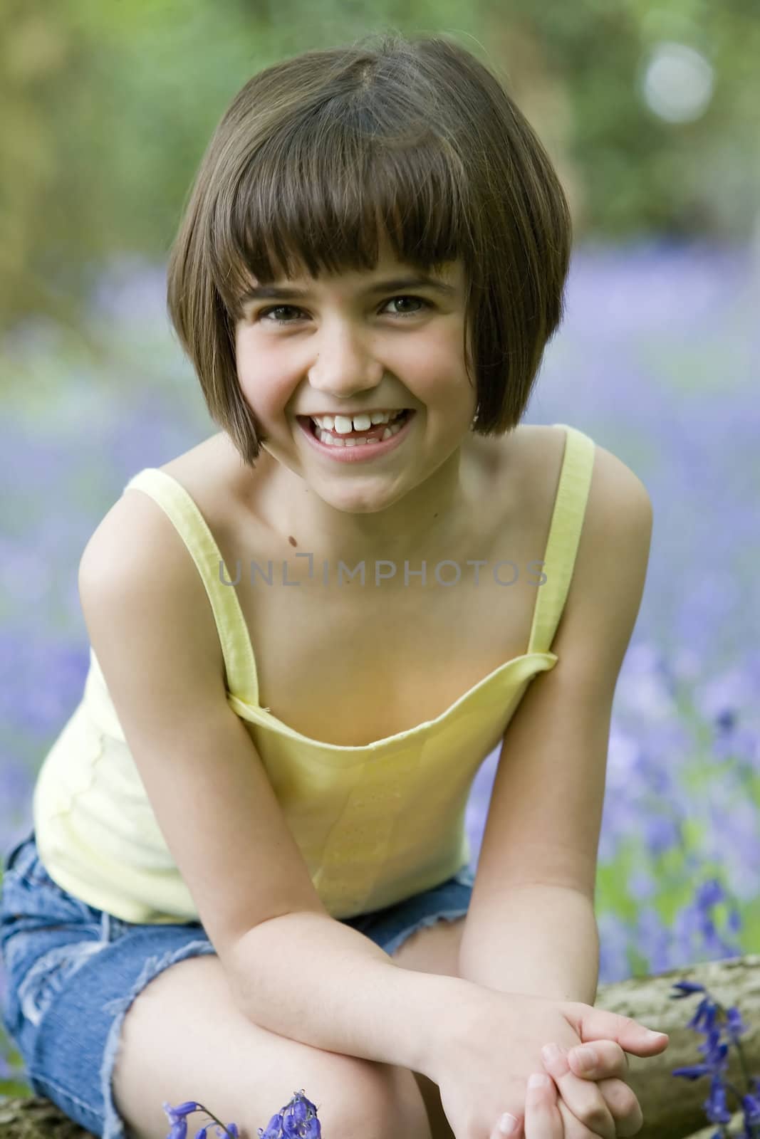 young female child sitting in a field of bluebells