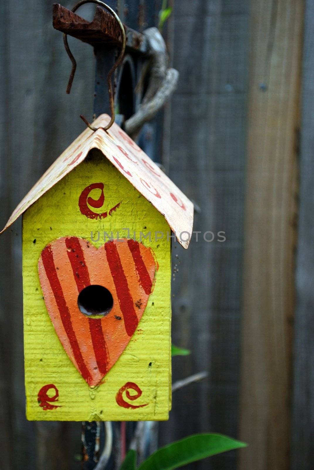 bright yellow bird house with a heart