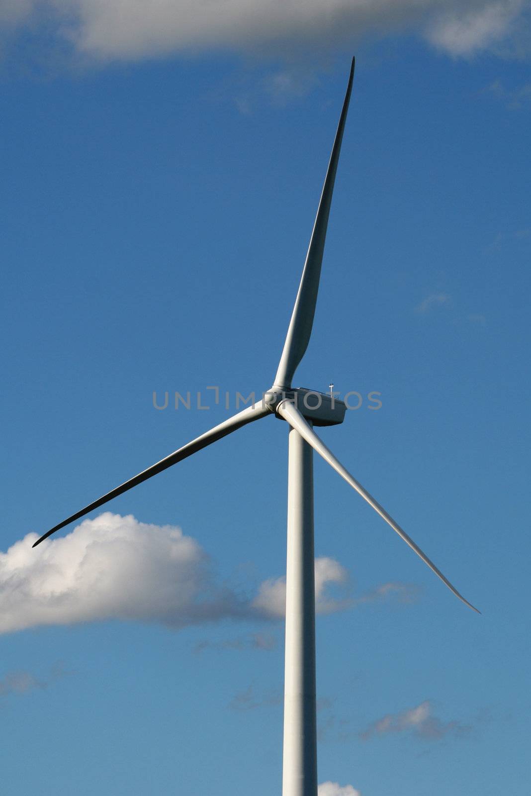 A close up of wind turbine shot against a blue sky.
