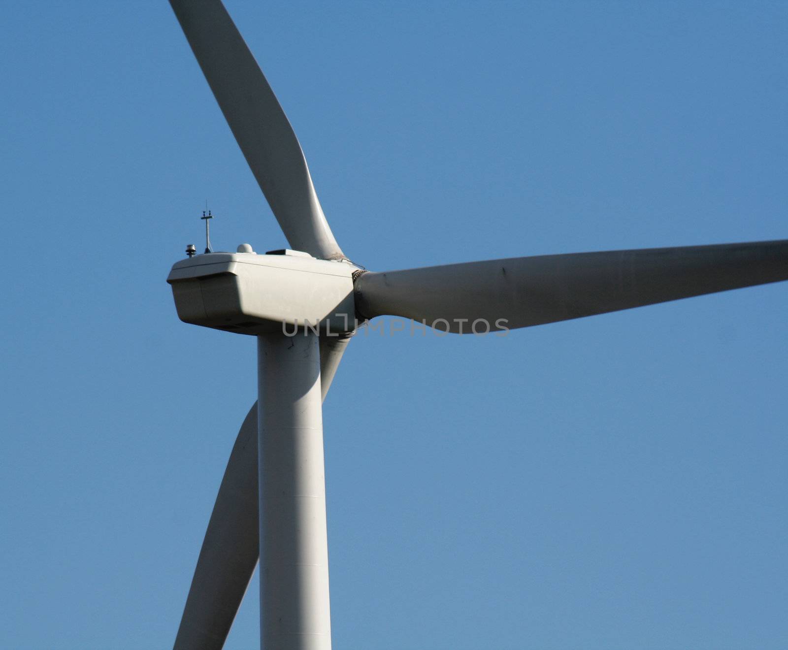 A close up of wind turbine shot from behind against the blue sky.