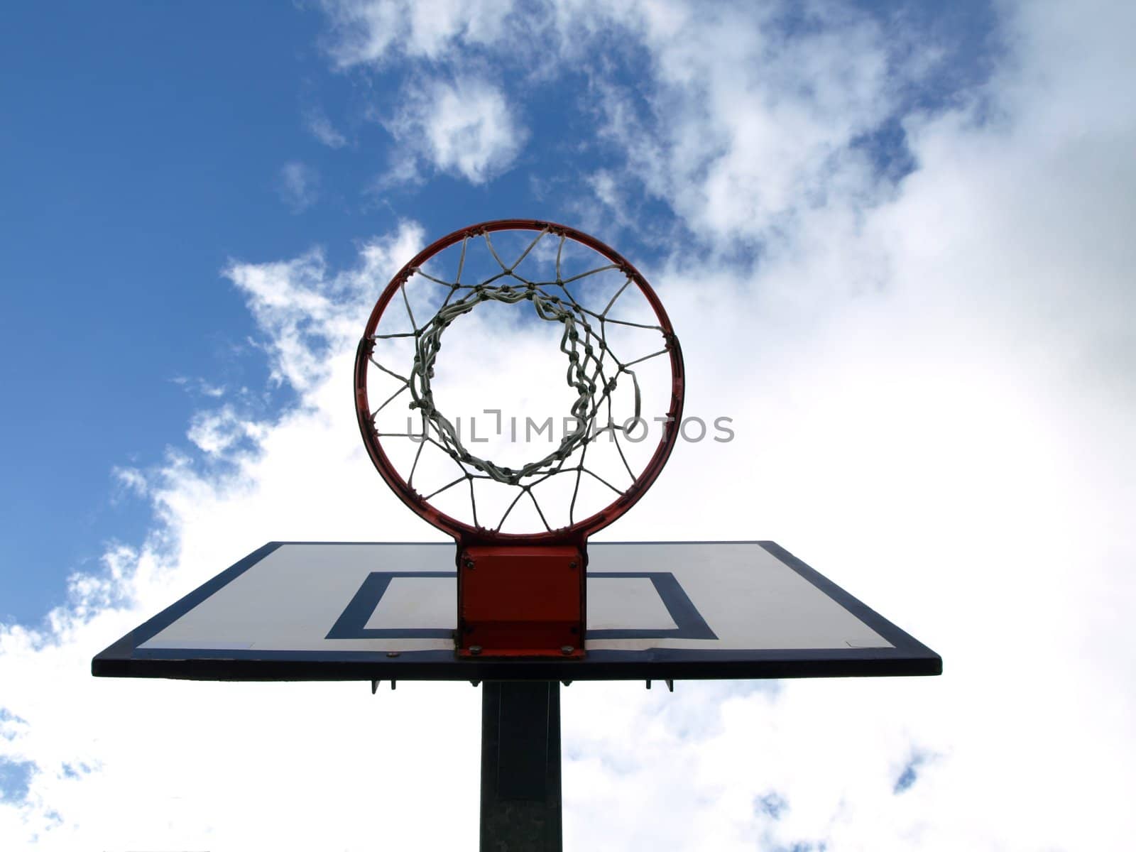 Basketball hoop under blue sky with clouds