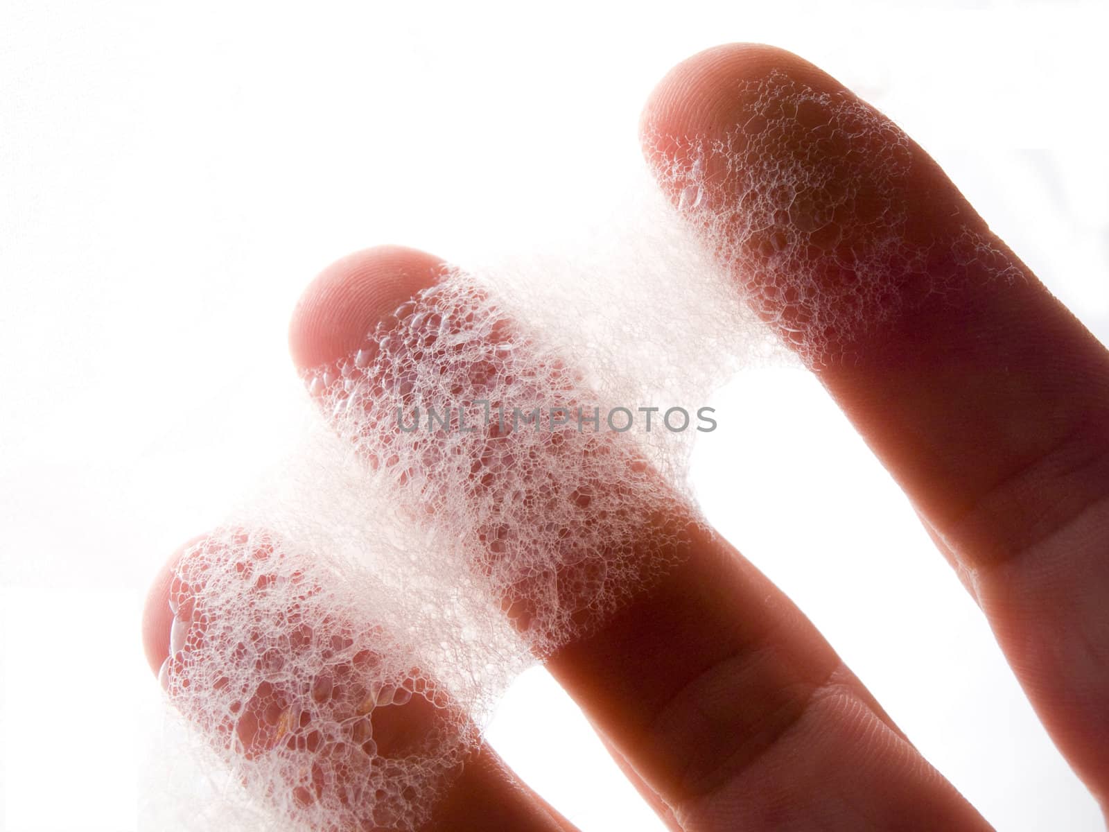 Macro shot of fingers holding soap bubbles isolated on white