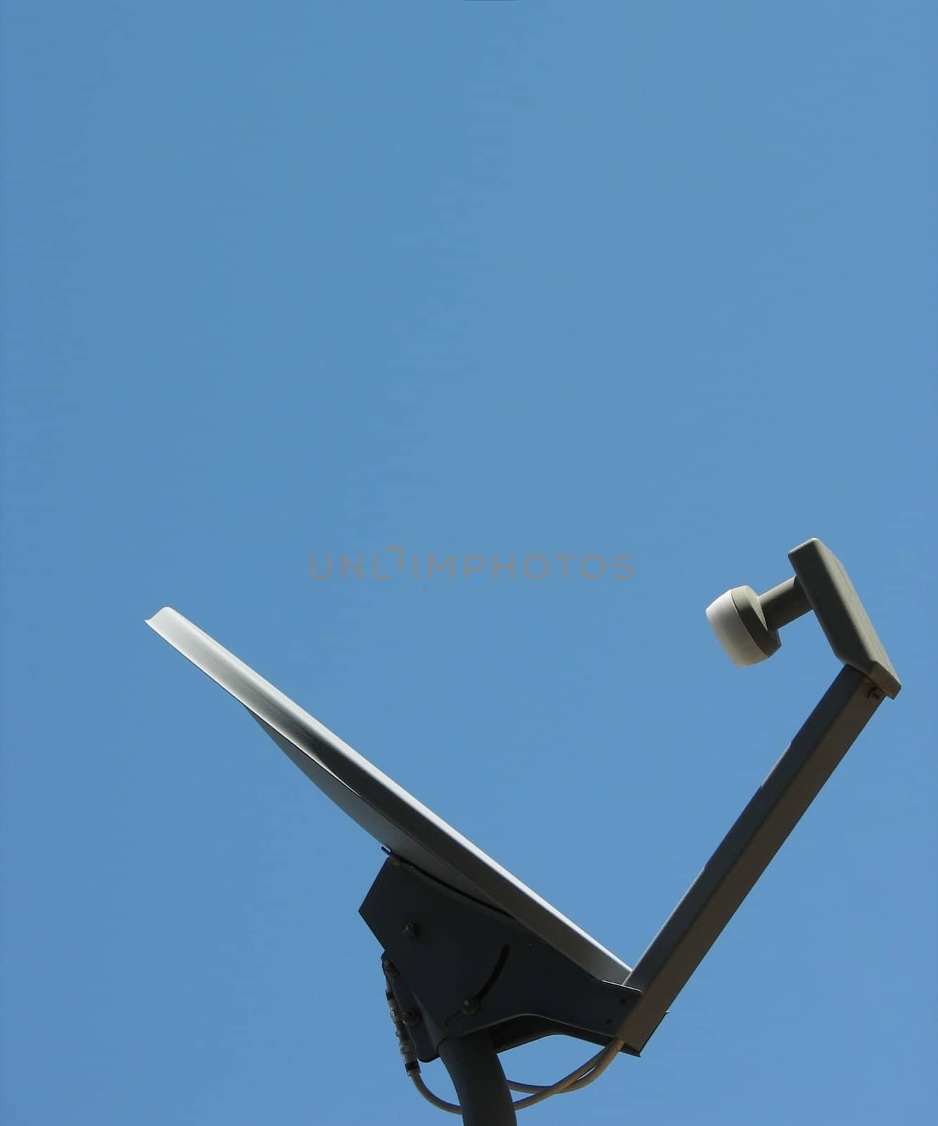 A satellite dish against a clear blue sky, horizontal orientation, listening.