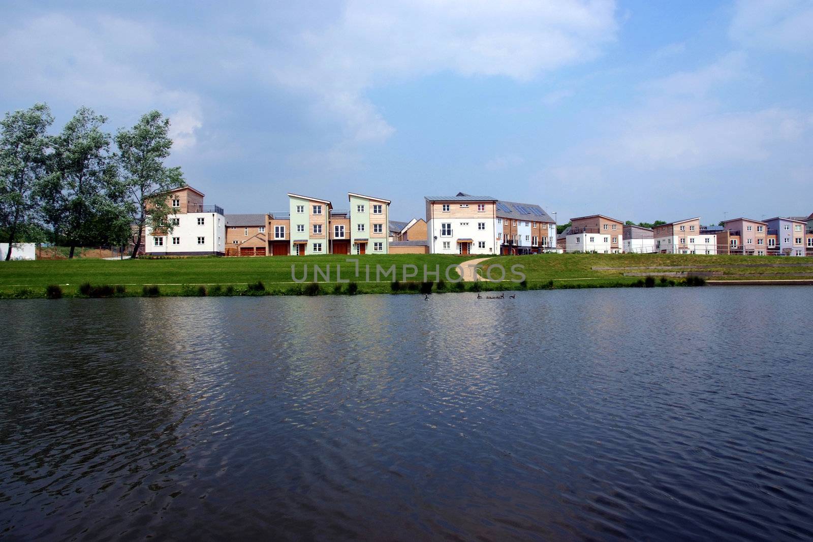 A development of modern housing with a lake in the foreground