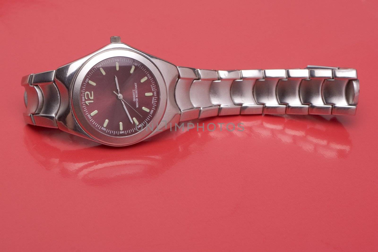 Men sport watch on it's side, reflecting on red surface