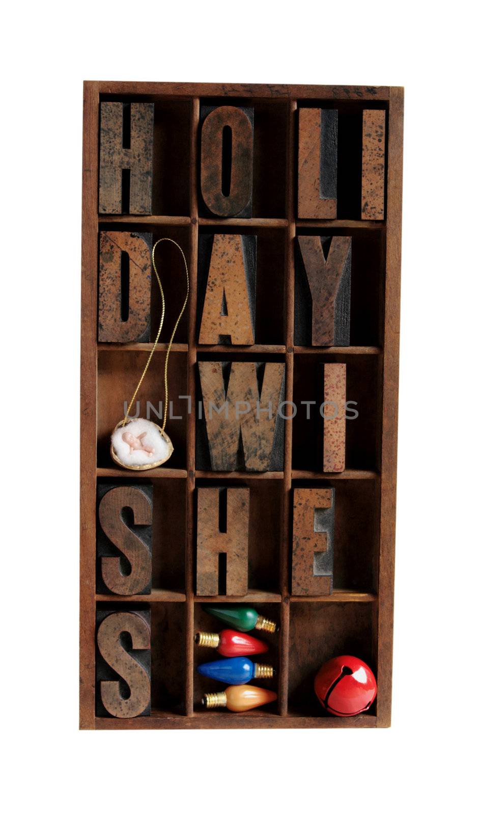 the phrase 'holiday wishes' in a type case with vintage Christmas light bulbs, a red jingle bell and a baby Jesus in a walnut shell