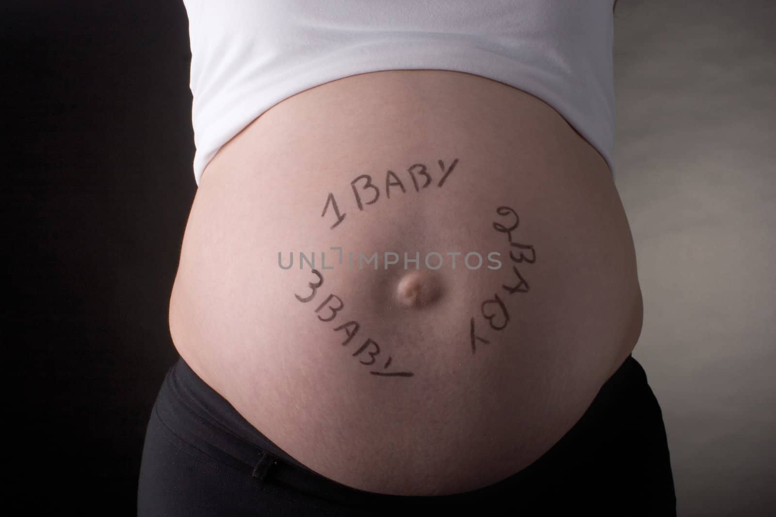 seven month pregnant belly with one baby, two baby, three baby written on the stomach