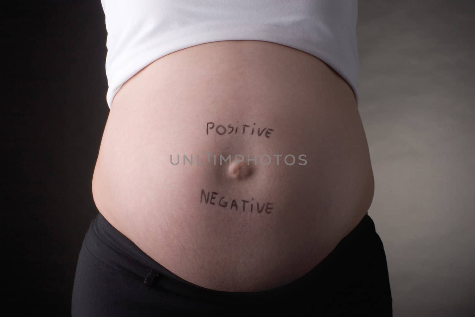 seven month pregnant belly with positive and negative written on stomach