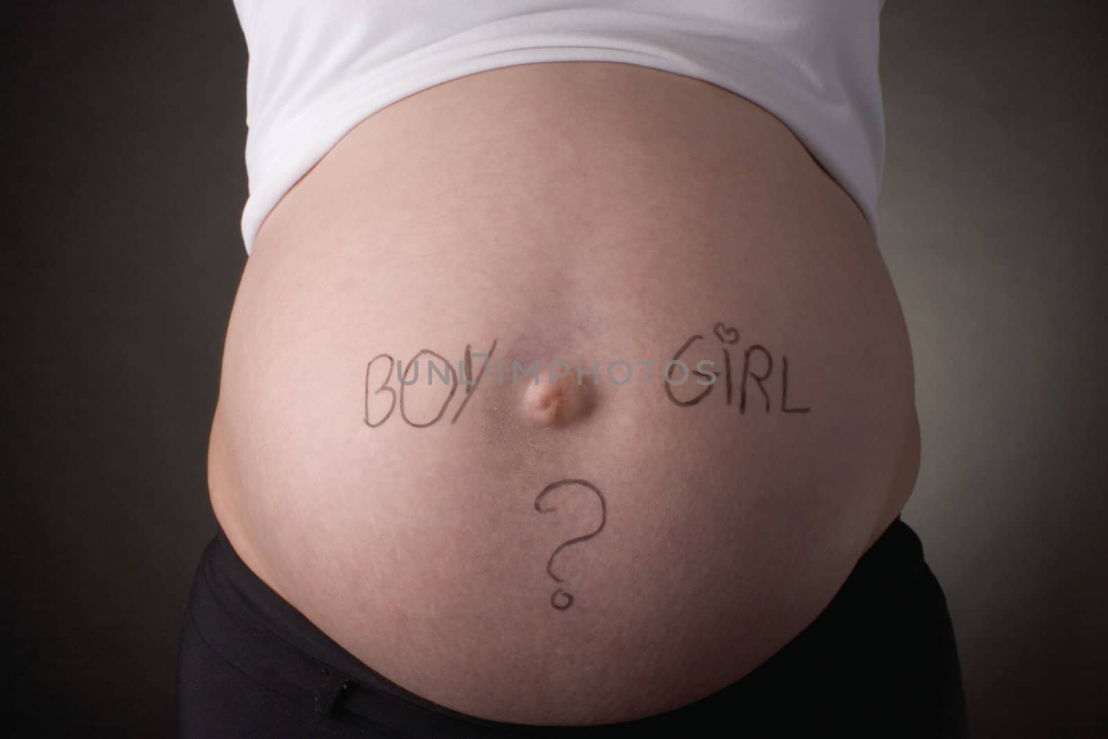 seven month old belly with the question boy or girl written on it
