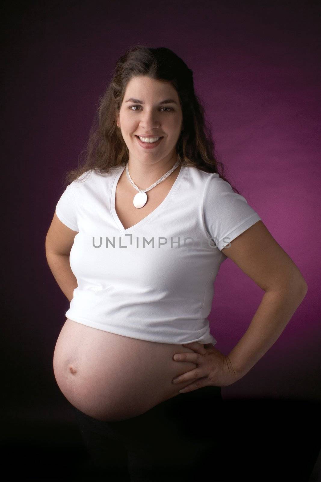 seven month old pregnant women smiling while showing her belly