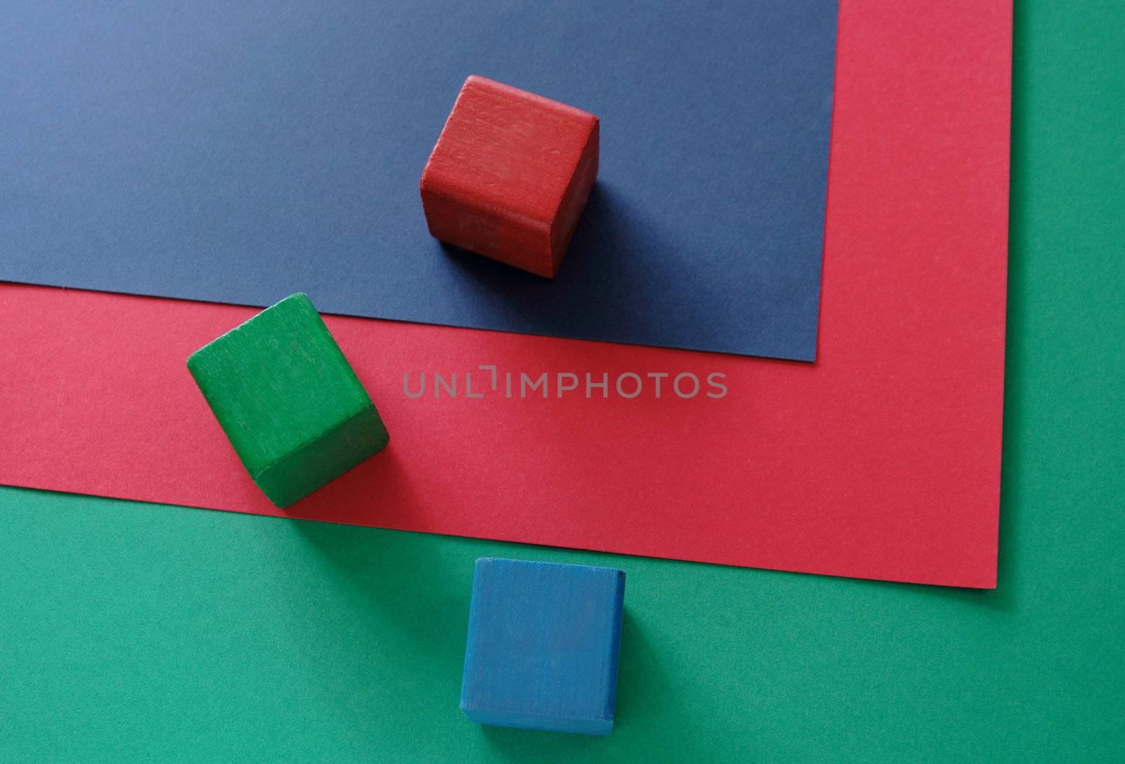 three blocks in red, green and blue on three sheets of red, green and blue paper