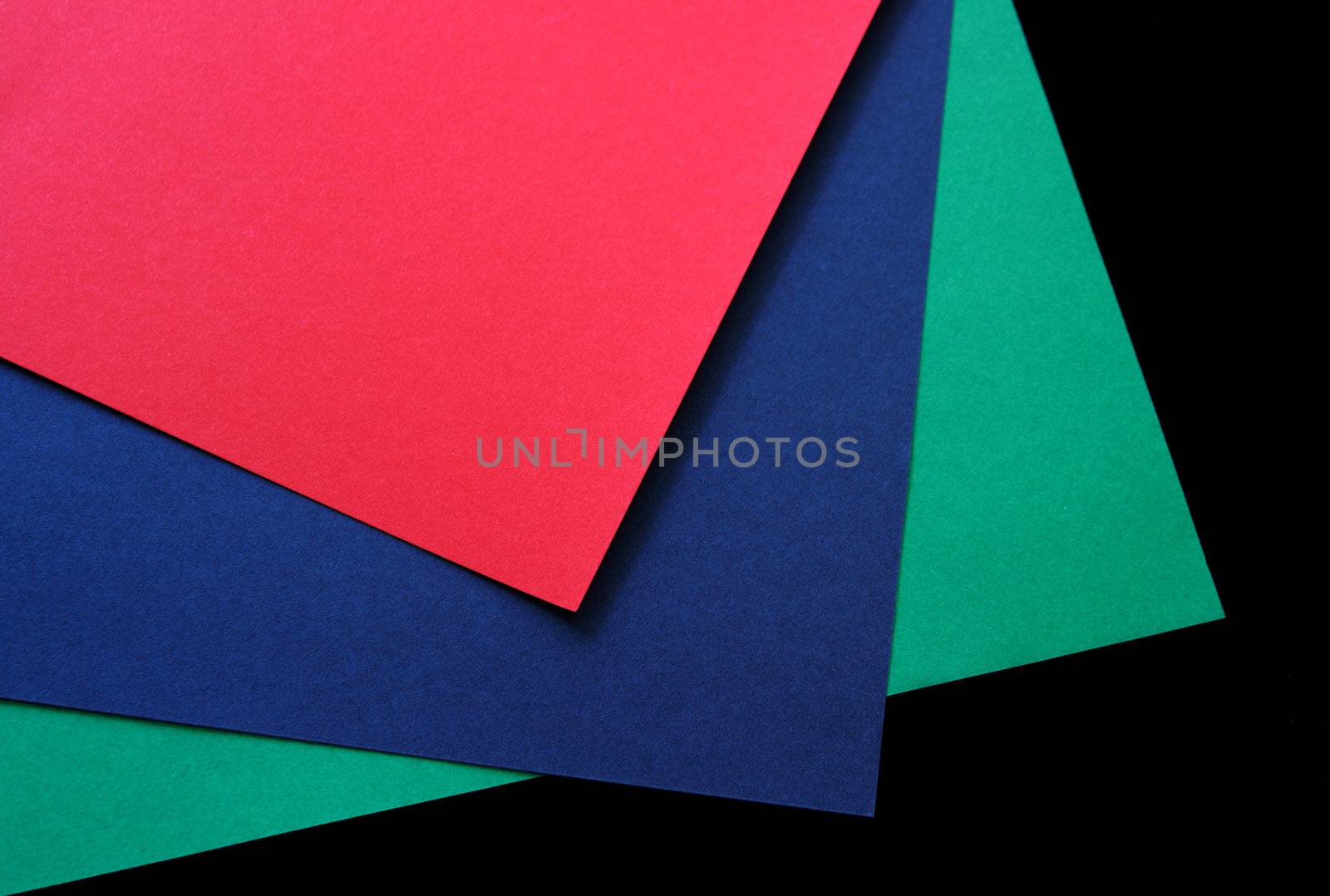 red, green and blue paper on a black background