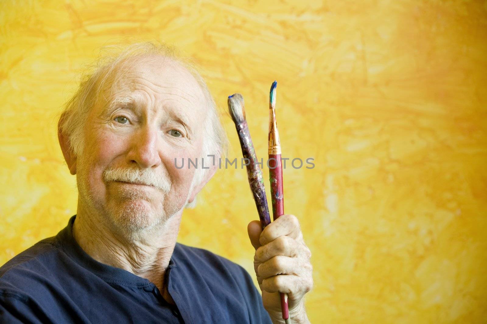 Portrait of an elderly painter wearing a beret holding paint brushes with copy space