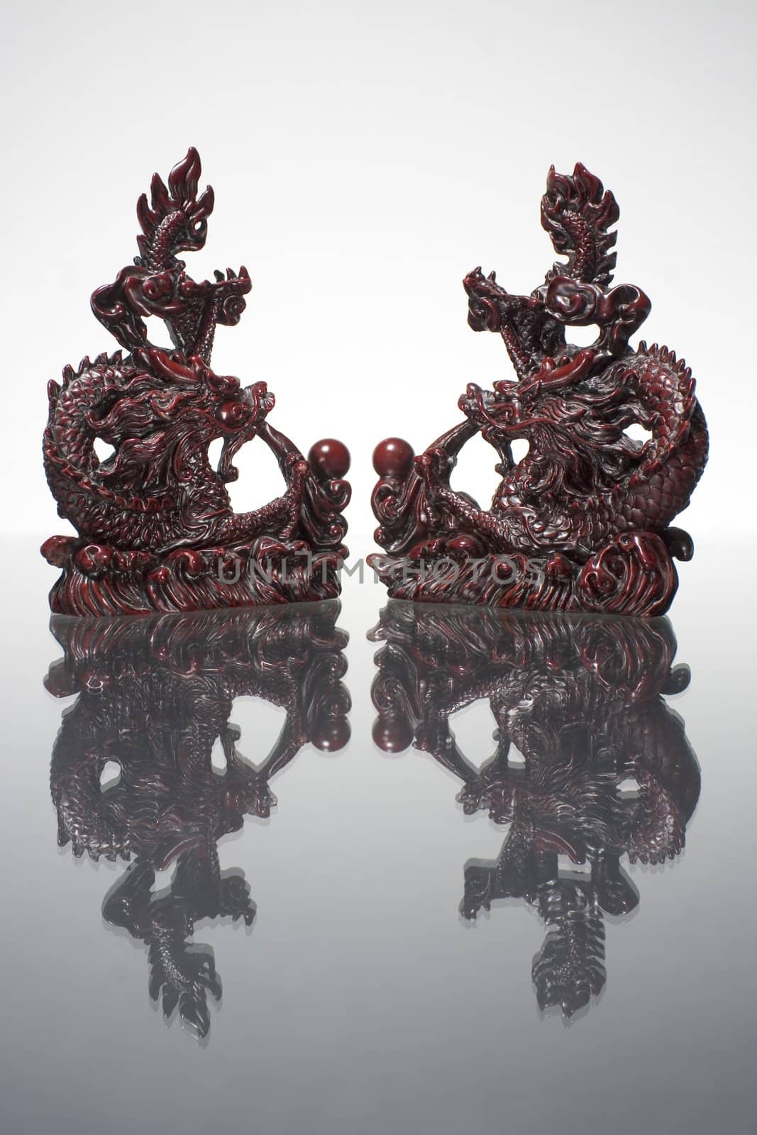 two dragon statue reflecting on a grey surface