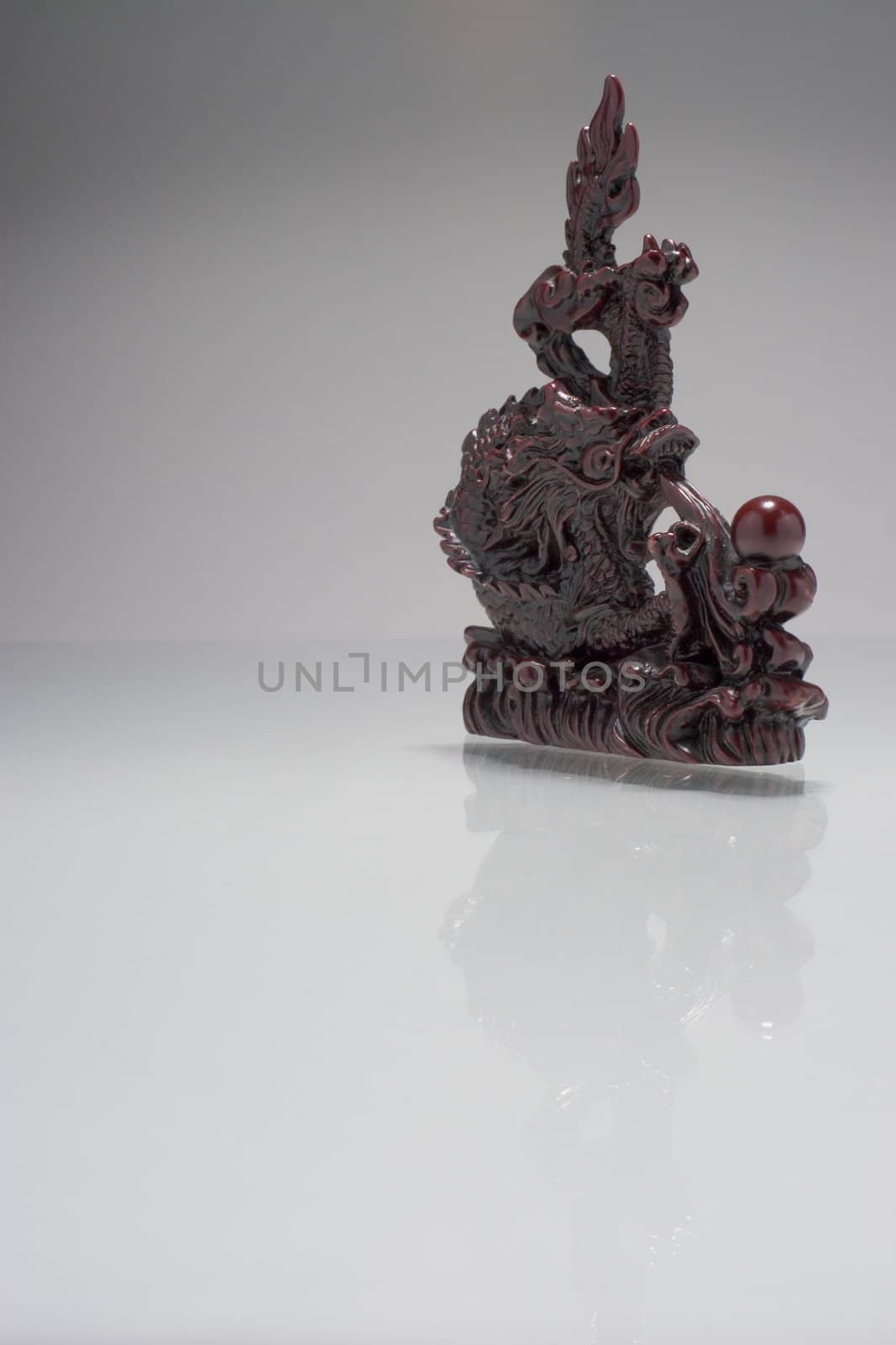 Asian dragon statue floating on a white reflective surface