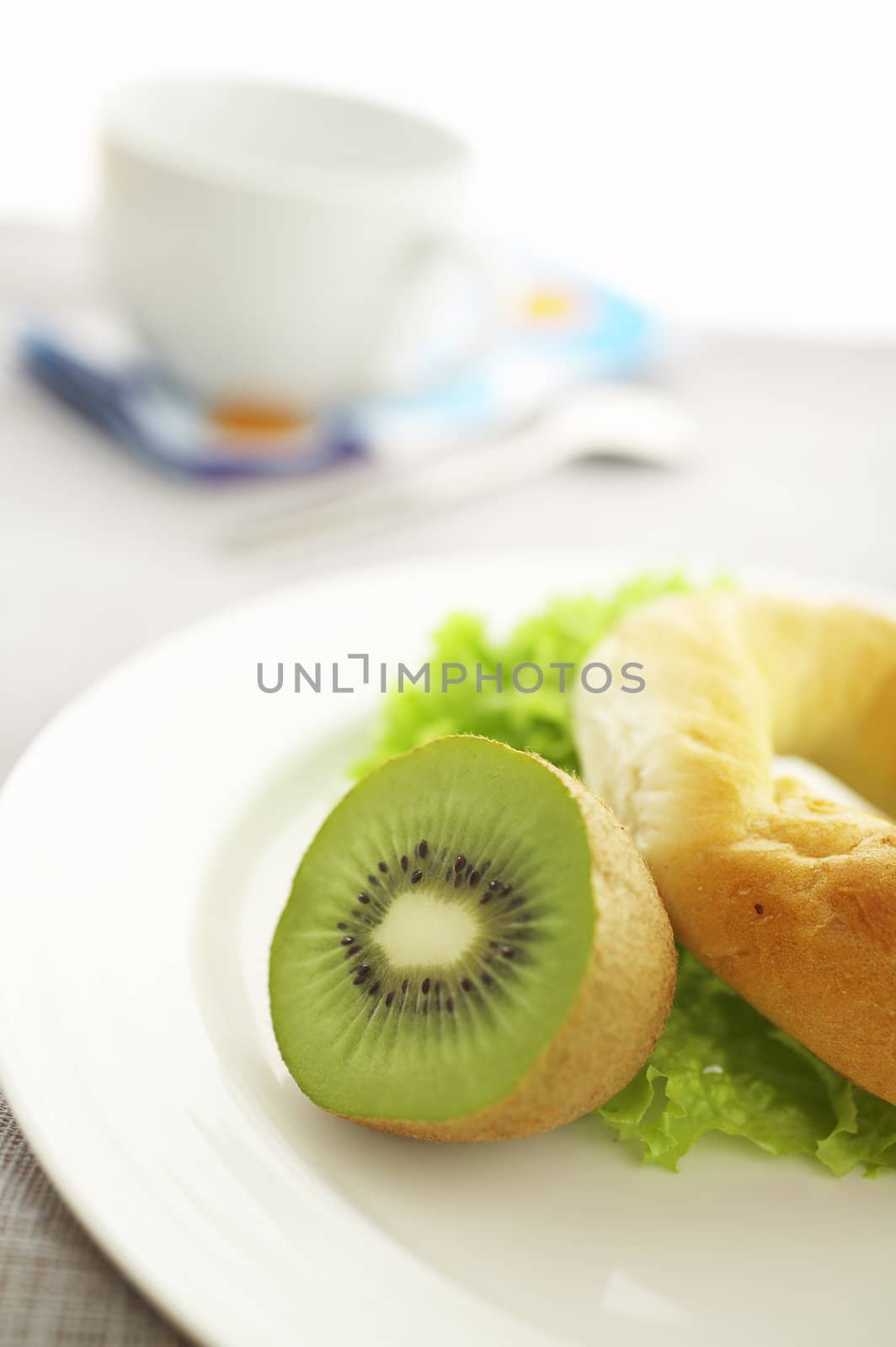 Breakfast on the table ( coffee, kiwi, bagel, salad ) 