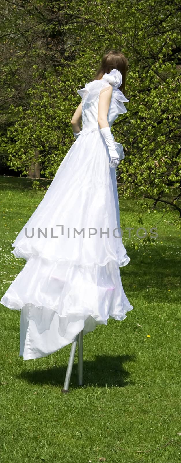 White woman on stilt in green park