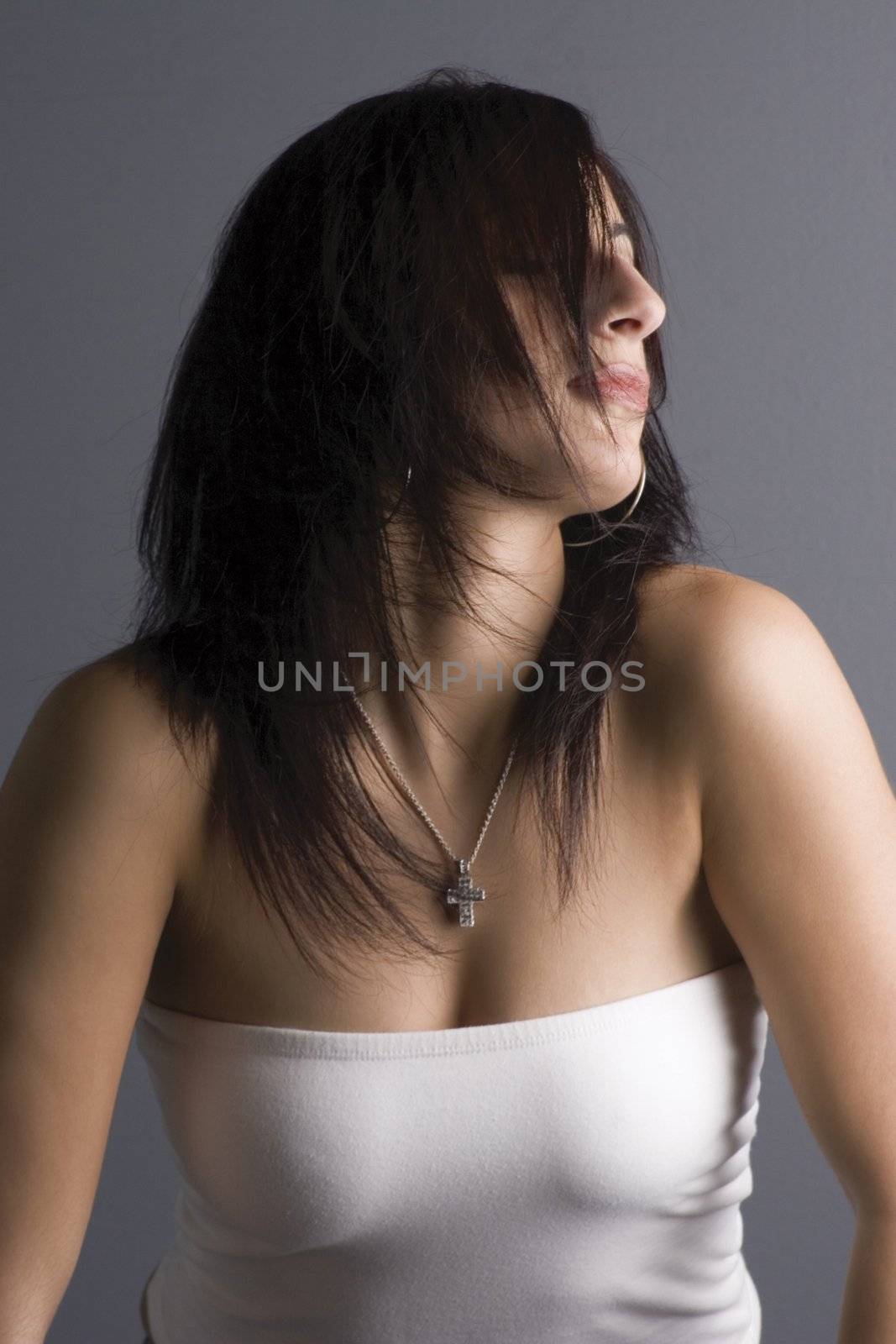 Twenty something fashion model in white tube top, flipping hair back in full motion