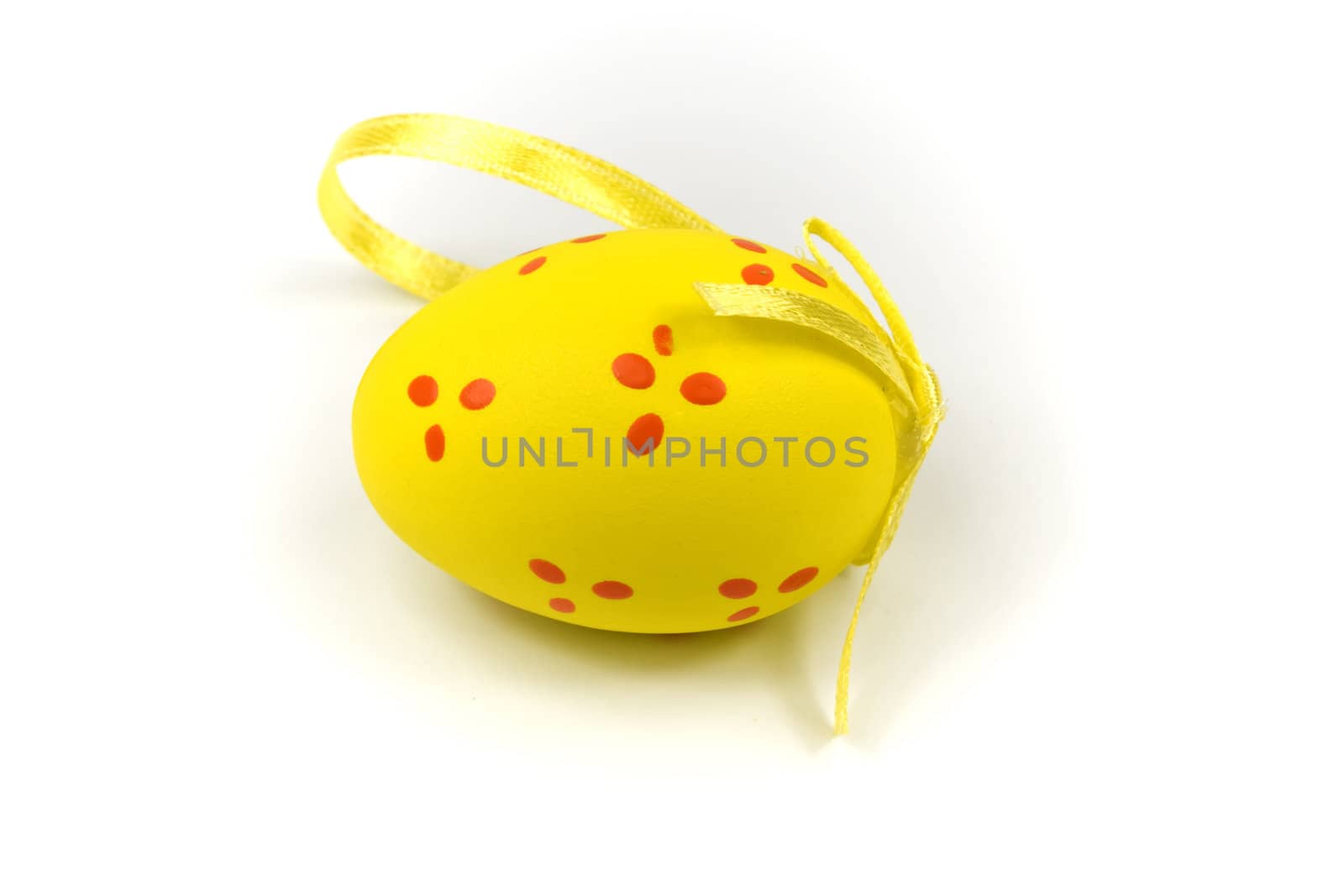 One yellow easter egg with gold ribbon isolated on white