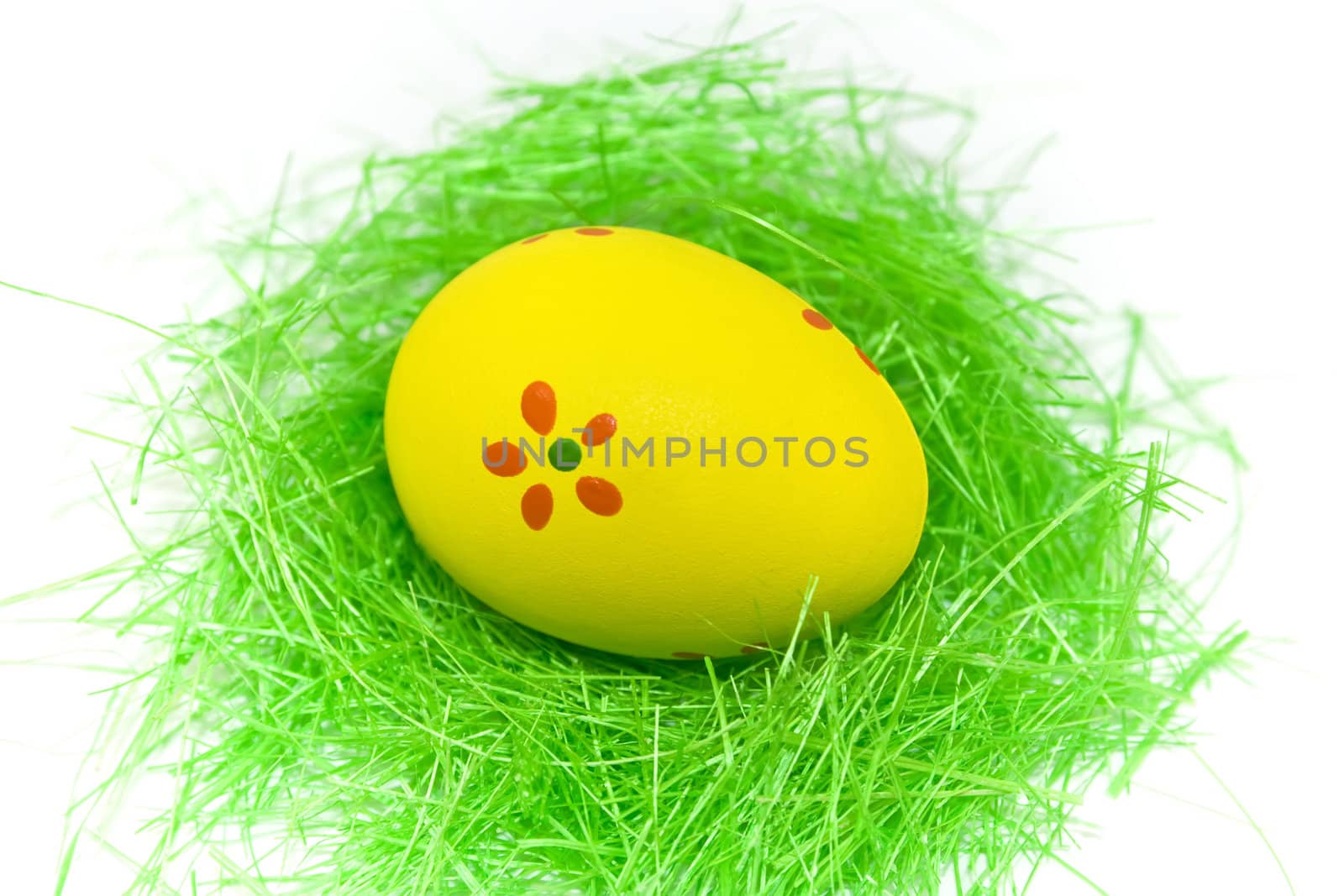 One yellow easter egg with green grass isolated on white