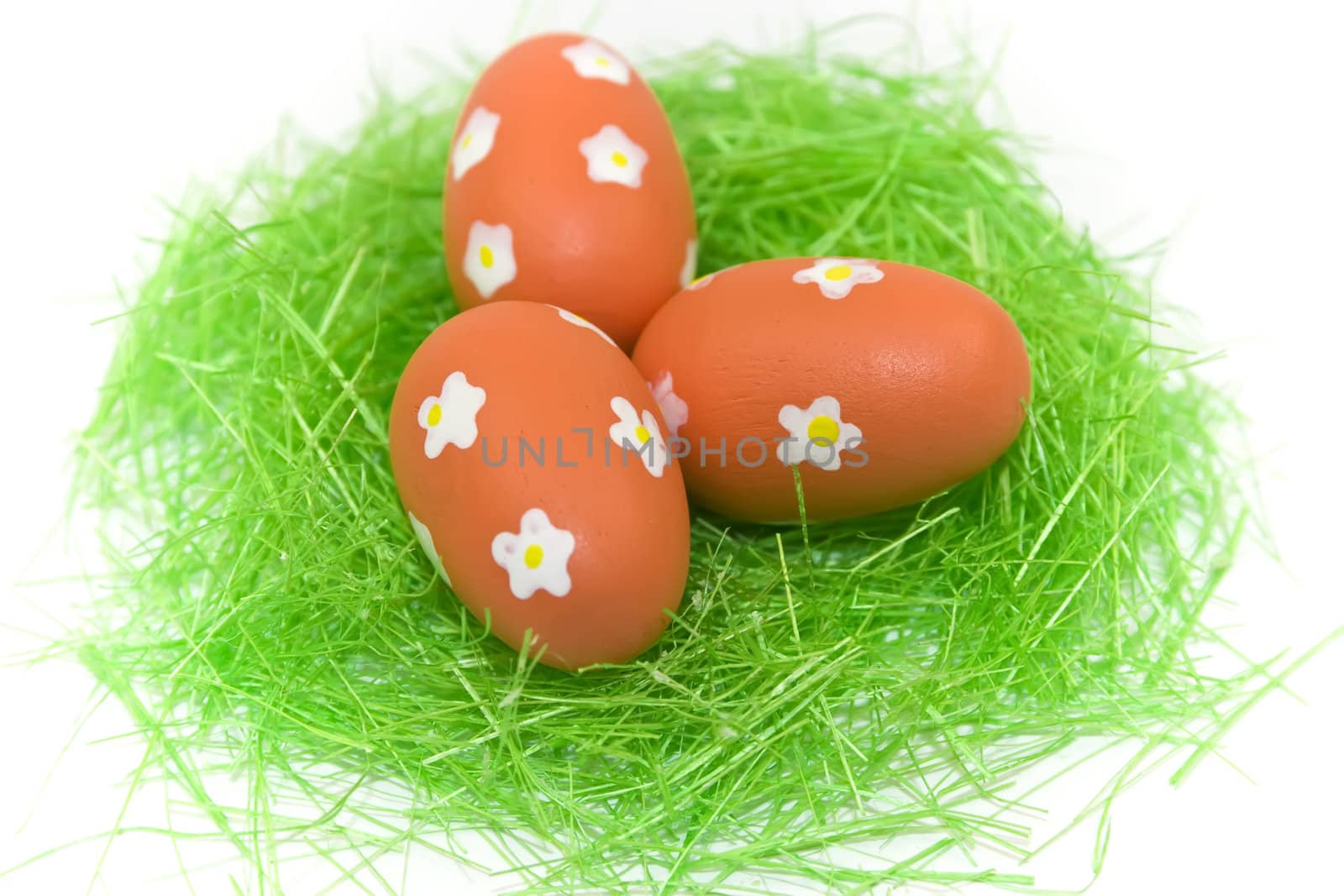 Three red easter eggs with green grass isolated on white