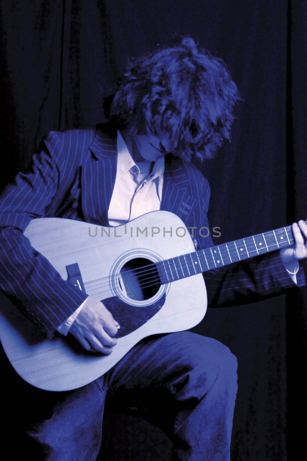 Young male model in a suit playing accoustic guitar.  Duotone blue with painting effect