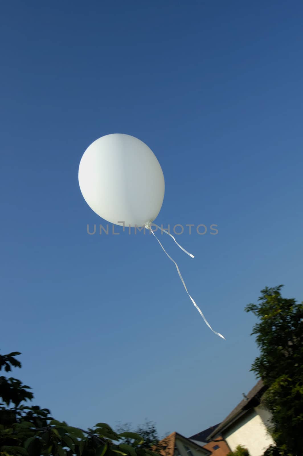 A child's balloon floats away into a clear blue summer sky. Space for text in the sky.