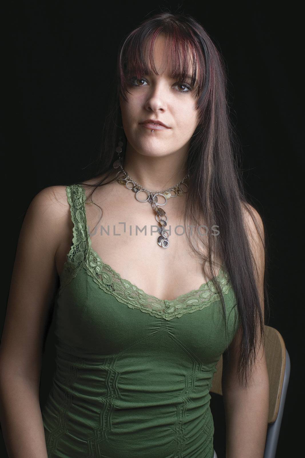 Close up portrait of fashion model in relaxe position with green tank top, sitting on a chair
