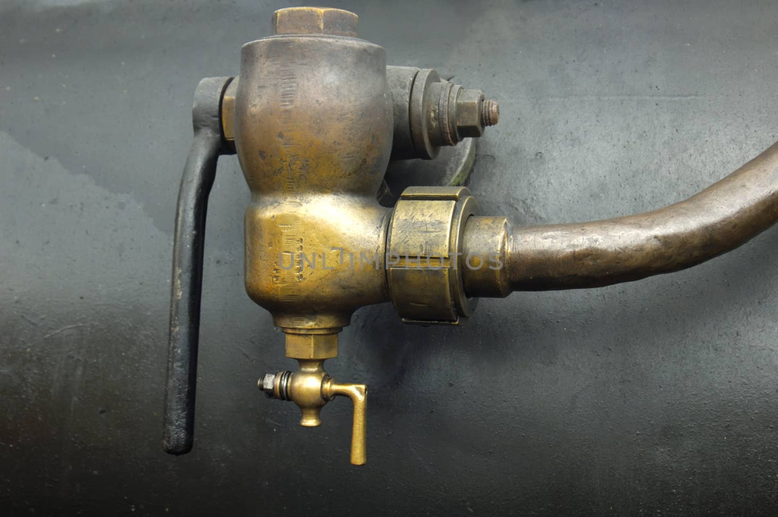 Detail of a brass valve, of unknown purpose, on the side of the boiler of an old steam engine.