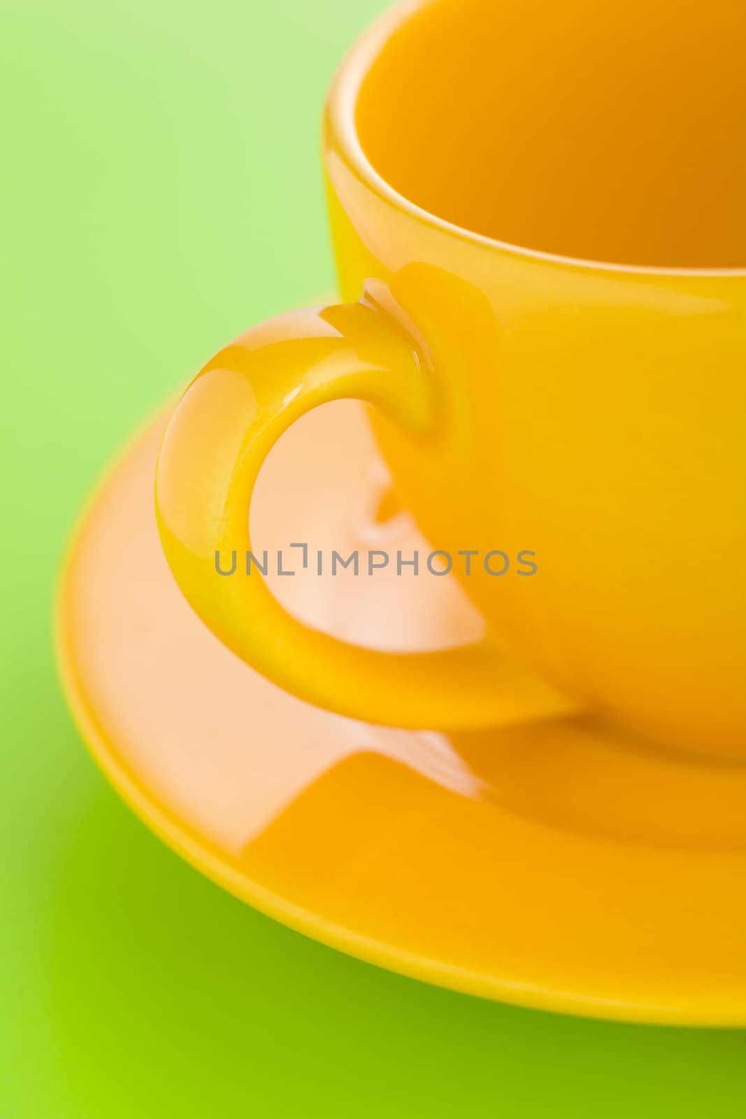 Empty yellow coffee cup over a light green background