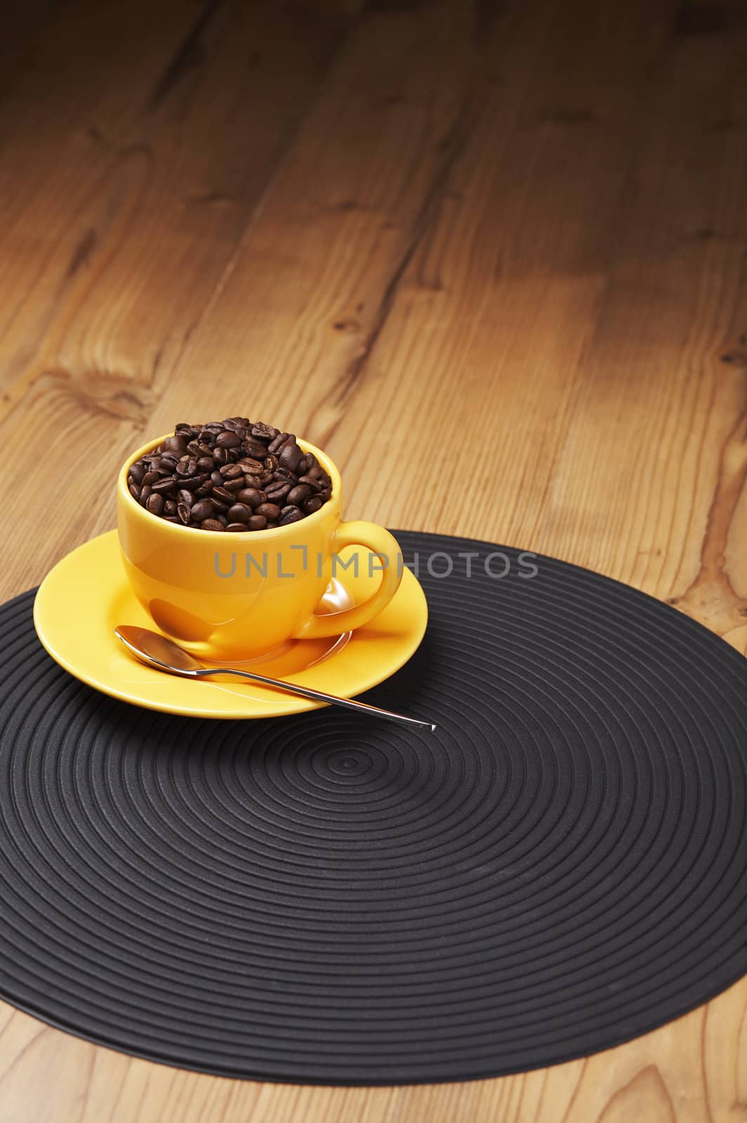 Yellow coffee cup filled with beans on a wooden table