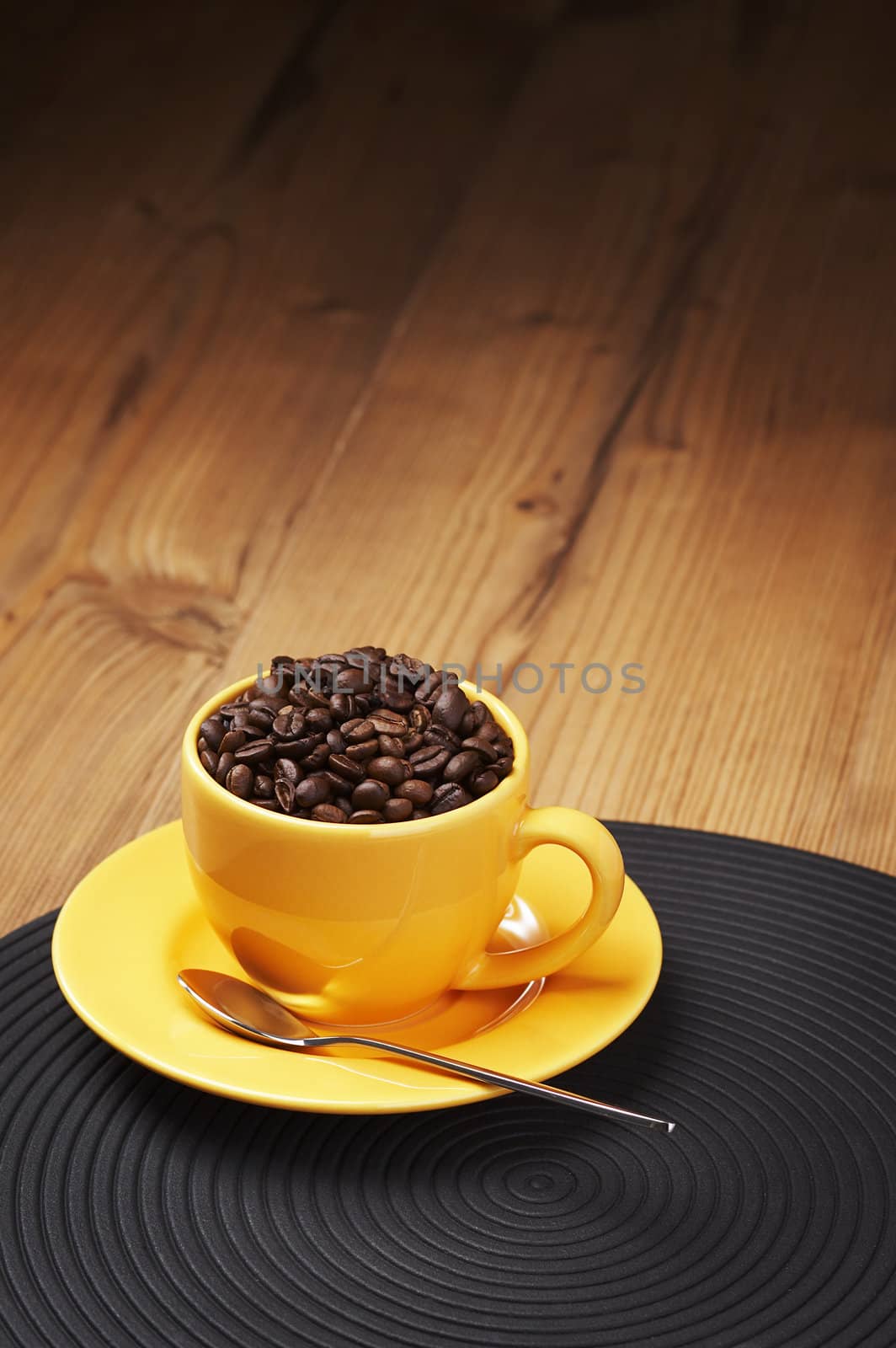 Yellow coffee cup filled with beans on a wooden table