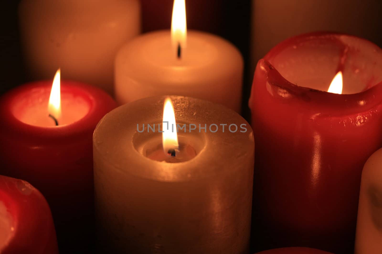 A group of burning candles, red and white