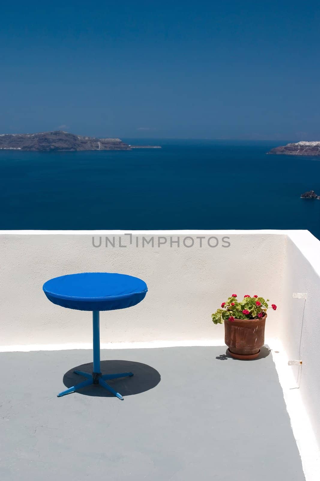 View from the balcony to Aegean Sea. Blue table and plant in vase standing on this balcony.